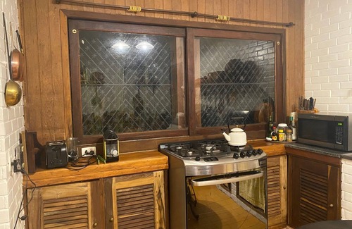 Correas Casa | Casa colonial con otras dos casas más pequeñas en el borde de un río y por el bosque.