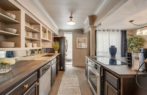 Lower Greenville Condominio | Upscale 2BR Dallas condo with pool view and access to an award-winning courtyard featuring a resort-style pool, hot tub, dry sauna, and lush lounge areas. Enjoy a 77″ smart TV, sleek leather sofa, and modern kitchen for a stylish, comfortable stay.