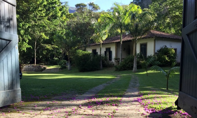 Correas Casa | Casa colonial con otras dos casas más pequeñas en el borde de un río y por el bosque.