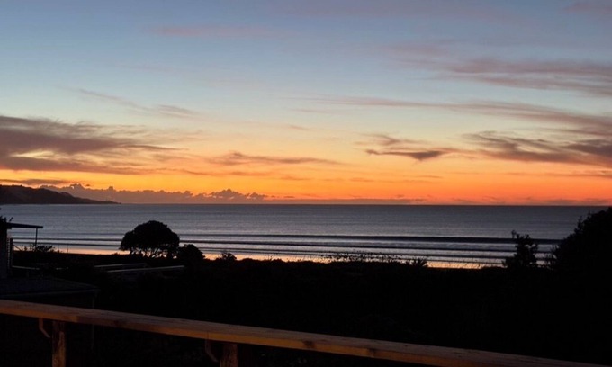 Ahipara Casa | Watch the waves from the large, sunny deck of this 1950's bach. Pet friendly.